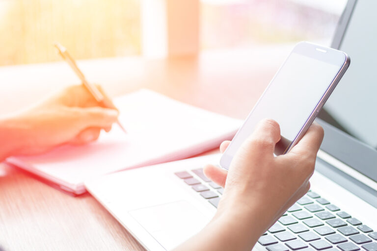 A Person Working on a phone and a laptop